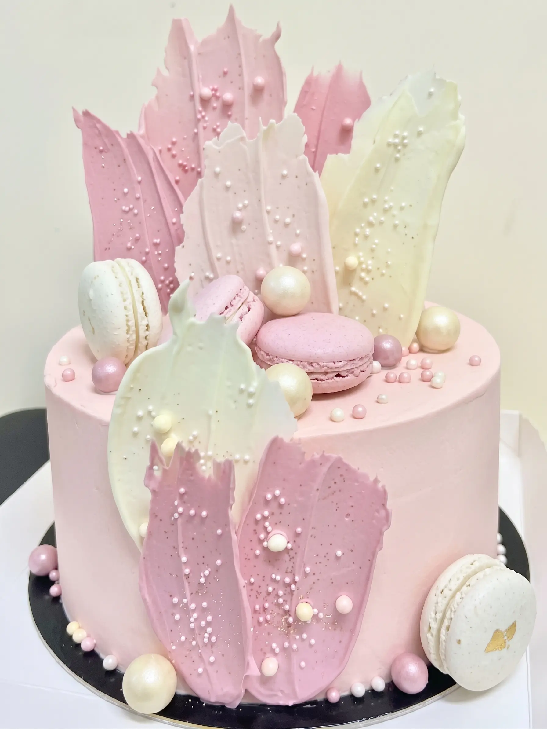 Pink special event cake decorated with macarons, pearl details and pastel chocolate shards